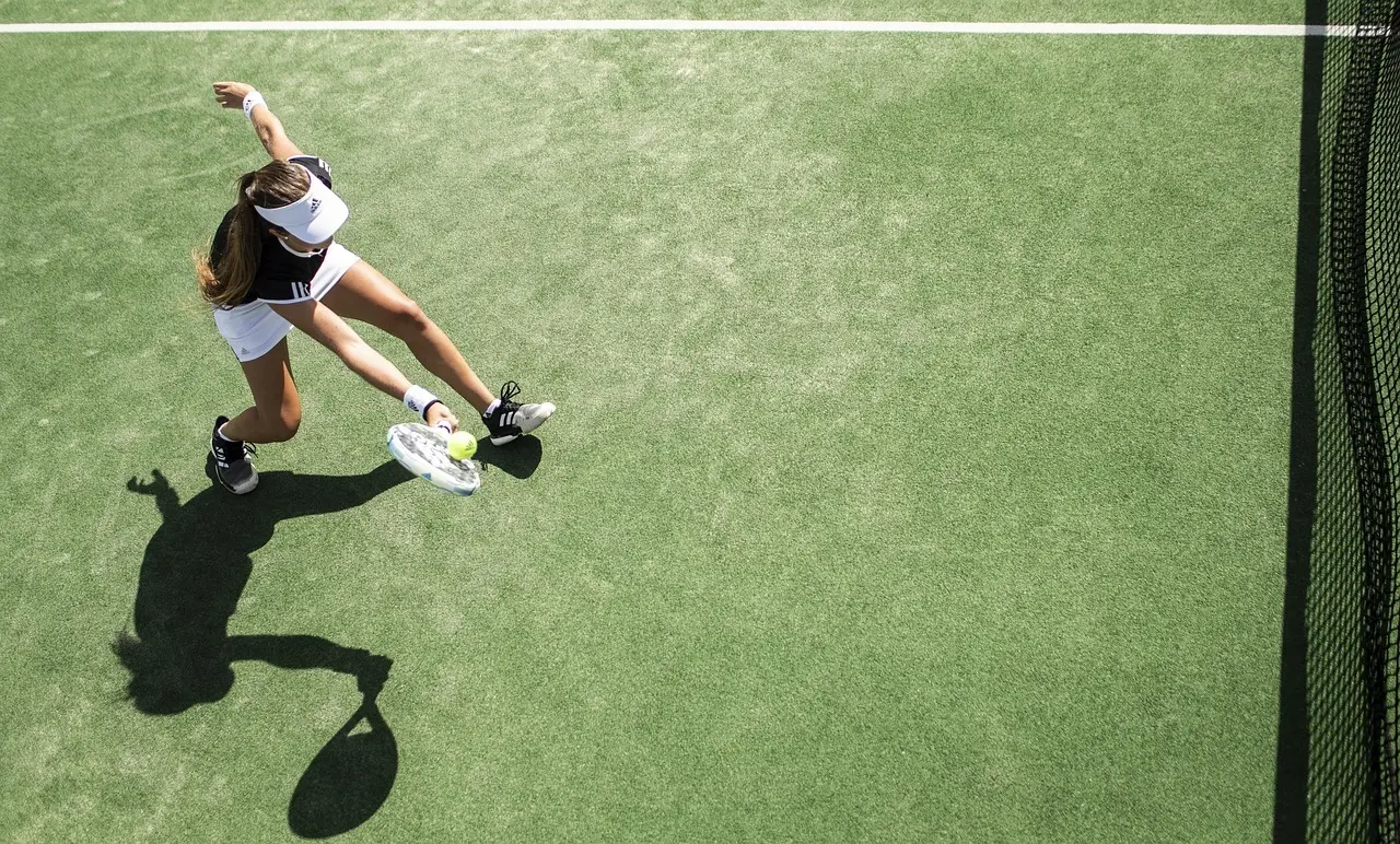 Kvindelig tennisspiller set ovenfra på grøn bane