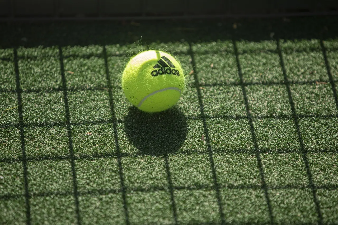 Tennisbold på grøn kunstgræsbane
