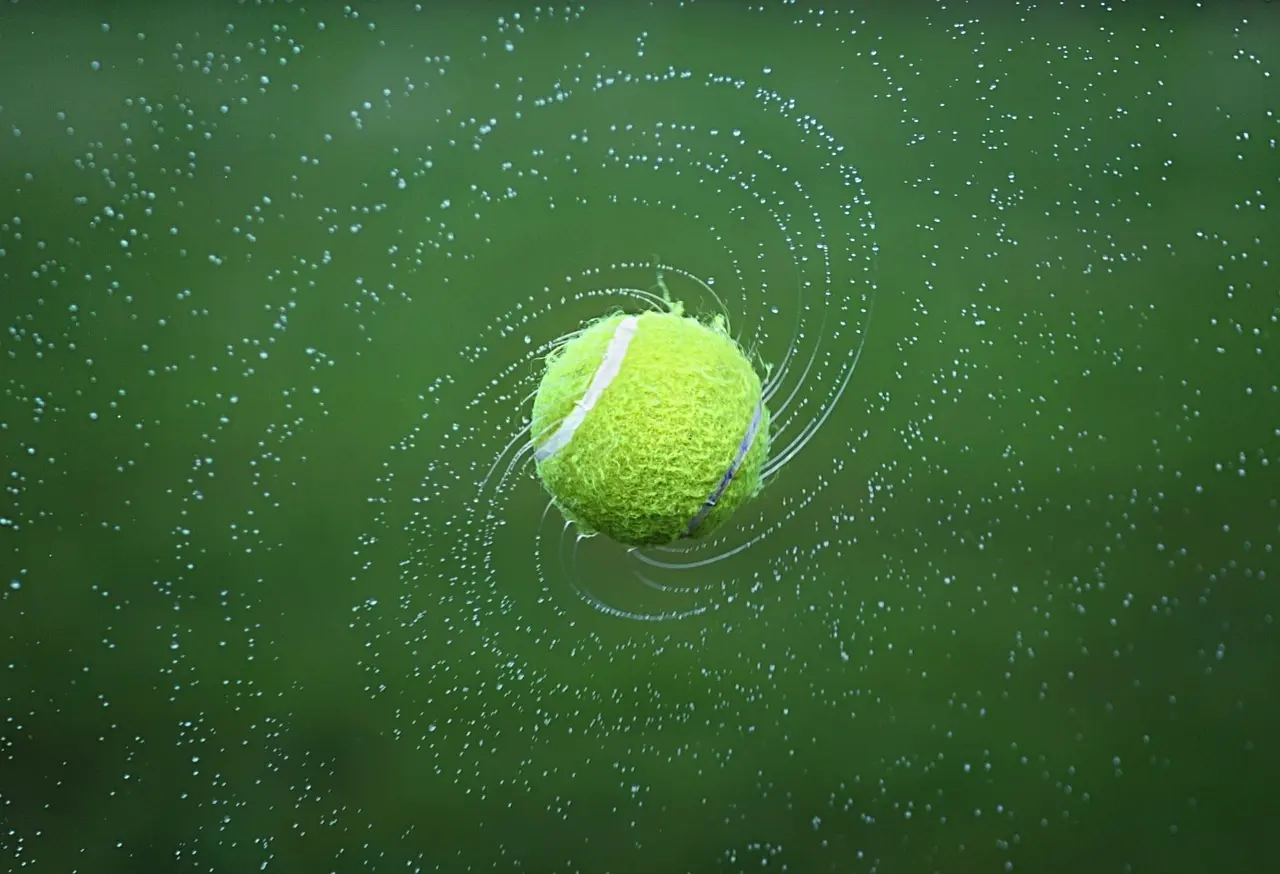 Tennisbold omgivet af vanddråber på grøn baggrund
