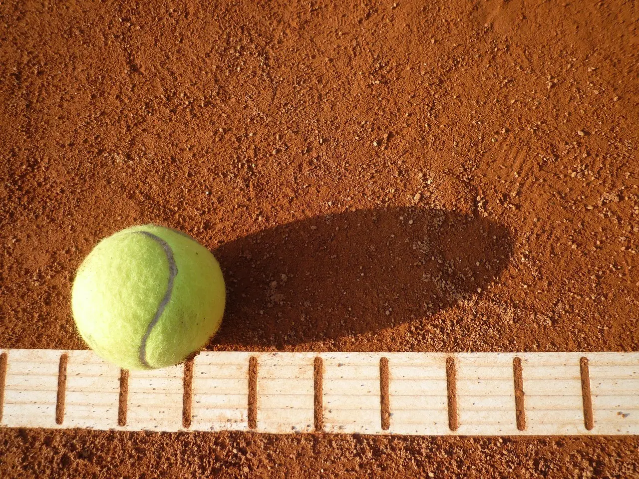Tennisbold på en grusbane ved en træplanke