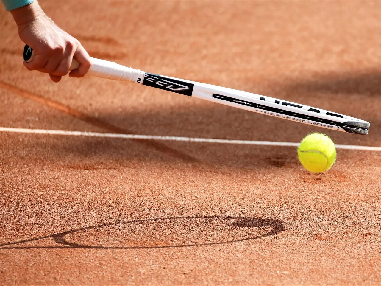 Tennisracket og tennisbold på grusbane